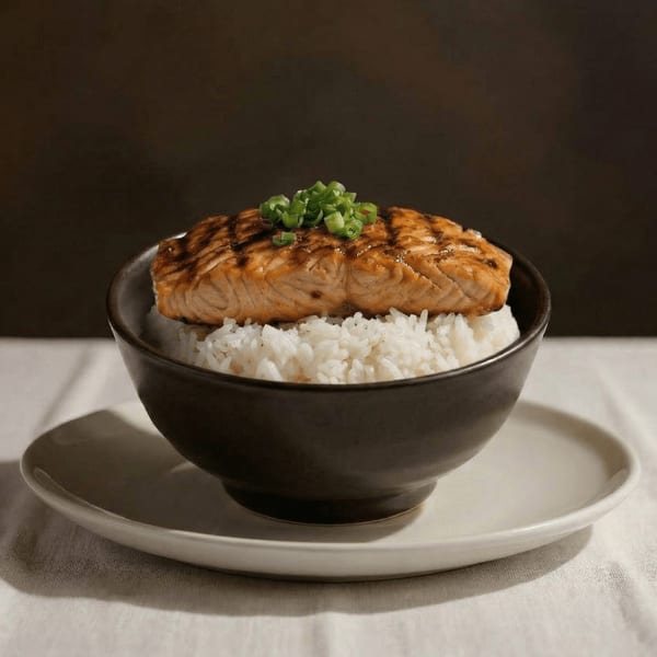 Grilled salmon with grill marks and chopped green onions, served over white rice in a dark bowl.